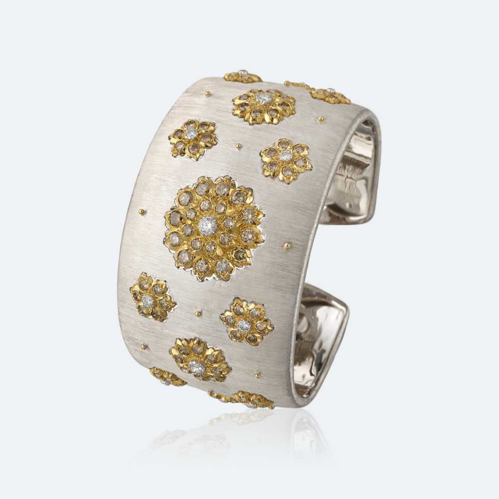Cuff bracelet in white gold, “rigato” engraved, with yellow gold flowers set with brown diamond, each one centering a yellow gold bezels set with a diamonds. Band width cms. 4,0. 109 round brilliant-cut diamonds cts. 5,45