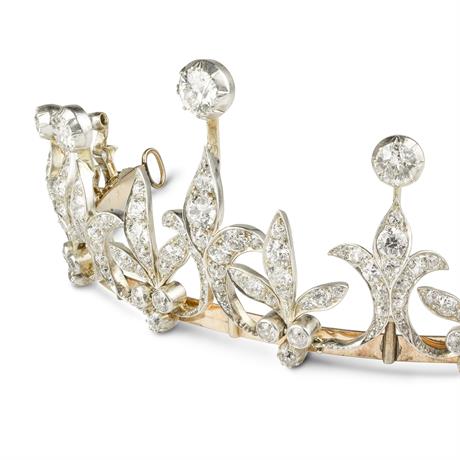 A late Victorian diamond tiara, the tiara comprising nine graduated diamond-set fleur de lys motifs with old brilliant-cut diamond tops, alternating with graduating diamond set leaf motifs with diamond trefoils to bottom, all to a gold frame with diamond set scalloped knife edge necklet back, diamonds estimated to weigh a total of 15 carats, set in silver to a yellow gold mount, with hidden side snap clasp, gross weight 65.6 grams, circa 1890.