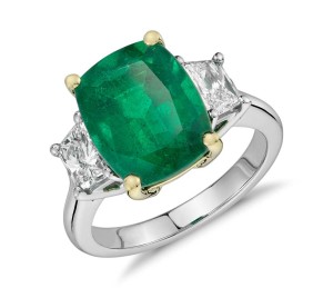 Cushion-Cut Emerald and Diamond Three-Stone Ring in Platinum and 18k Yellow Gold (4.90 ct center) (12x9.5mm)     One-of-a-kind elegance, this gemstone and diamond ring features a vibrant cushion-cut emerald complemented by brilliant trapezoid diamond side stones set in a classic platinum and 18k yellow gold design. 