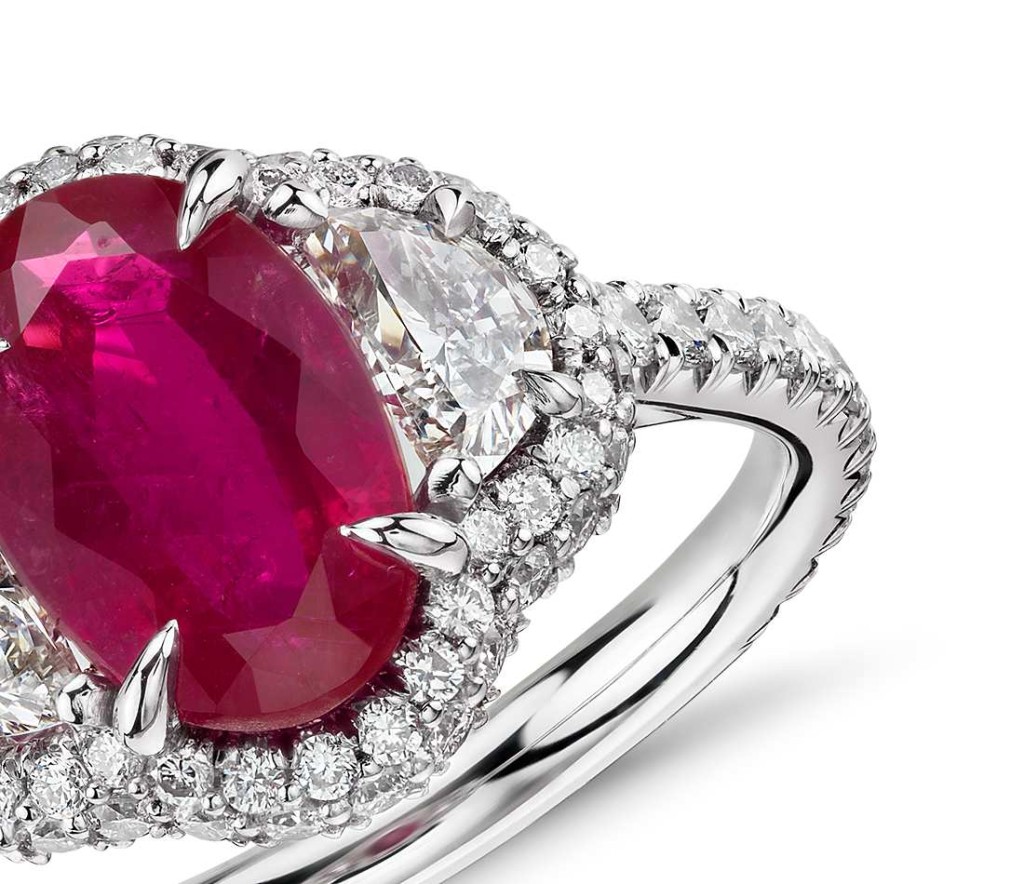 Uniquely stunning, this gemstone ring showcases a lively 2.24 carat oval ruby and two brilliant half-moon diamonds surrounded by halo of pavé-set round diamonds set in platinum with an 18k yellow gold accent. The exquisite ruby is a scarce, non-heated gemstone