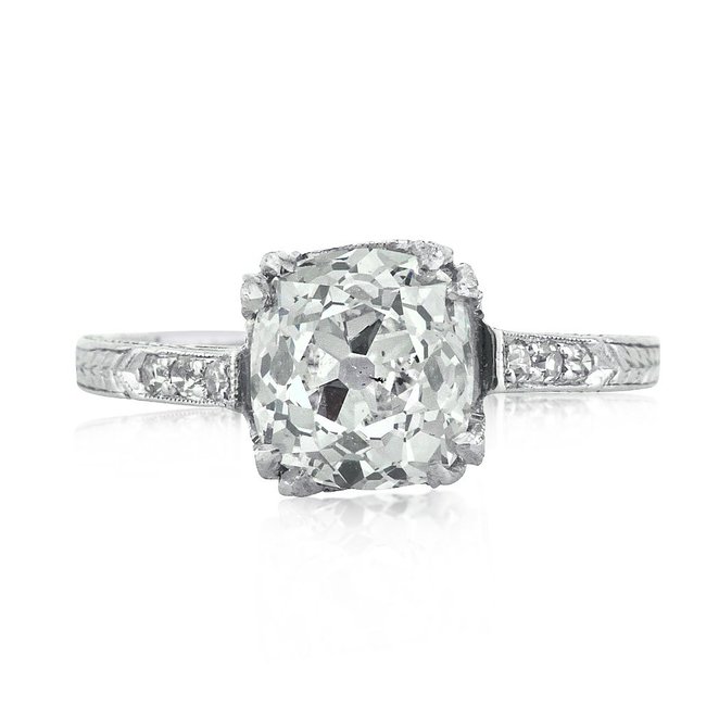 Enchant your sweetheart with vintage charm. This gorgeous old mine cut engagement ring is a sweet beauty with a lot of character. The antique style platinum setting has a few old round cut diamond accents and is covered in lovely hand engraving. Sitting pretty atop the setting is a glamorous 2.02ct old mine cut GIA graded at I-SI1. The cushion shaped stone faces up very white and brilliant. The facet pattern is true to old cut stones and is quite stunning. Seal your love by presenting her this one-of-a-kind antique style ring.