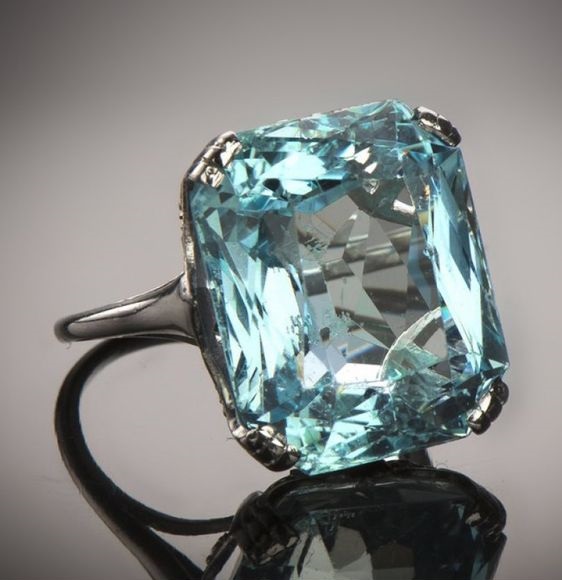 An Art Deco platinum, aquamarine and diamond ring, French, circa 1930. Set to the centre with a cushion-shaped aquamarine weighing 15 carats. 