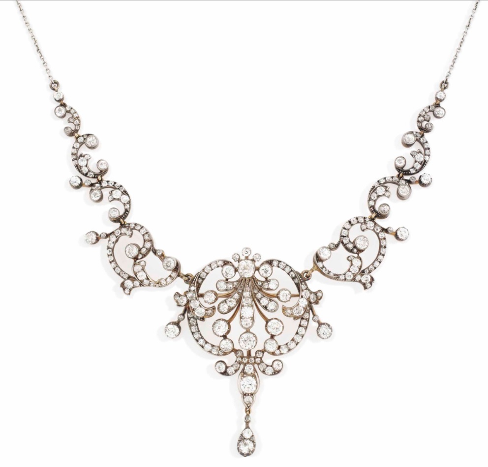 A late 19th-century diamond tiara / necklace. The graduated scrolling old-cut diamond-set panel, with central stylised shell motif and trefoil surmount, to a pear-shaped diamond-set finial, with associated fine-link chain necklace, mounted in silver and gold, central panel detaching to form a pendant / brooch, later adapted, tiara frame deficient, circa 1880, 40.2 cm. Sold for £8,125 on 2 December 2015 at Christie’s in London